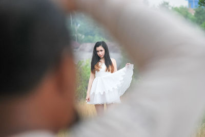 Young woman wearing white dress seen through man arm