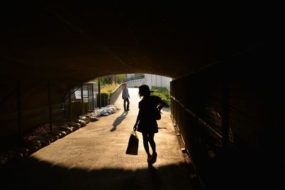 Rear view of woman walking in tunnel