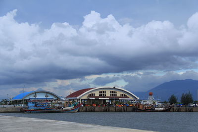Scenic view of river by buildings against sky