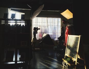 Woman photographing man in clothing studio