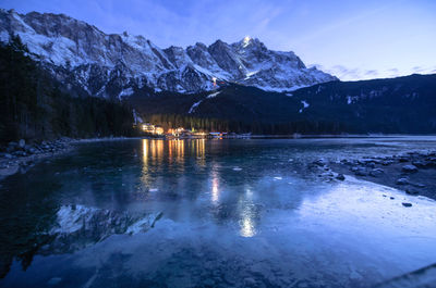 Scenic view of lake by snowcapped mountains against sky