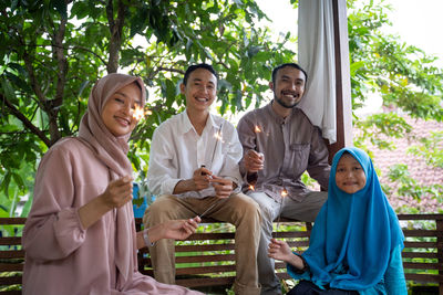 Portrait of smiling friends standing against trees