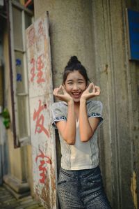 Portrait of smiling young woman standing against built structure