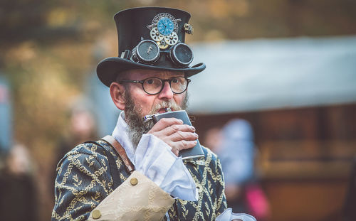 Portrait of man wearing hat drinking with hip flask at event