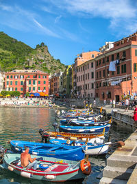 Boats moored at river by buildings against sky