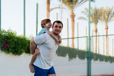 Happy father carrying son on back at sports ground