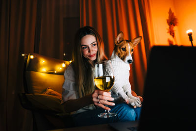 Woman holding wineglass doing video conference at home