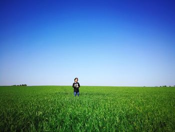 Girl standing on field against clear sky