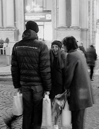 Rear view of friends walking on sidewalk in city