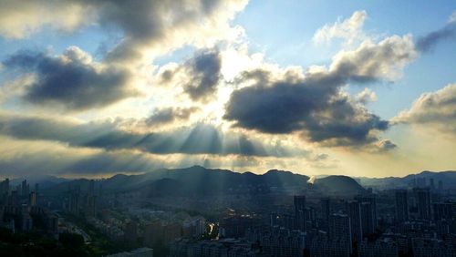 Cityscape against cloudy sky at sunset