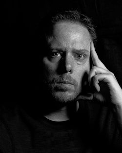 Close-up portrait of serious man against black background