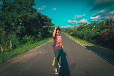 Full length of woman standing on road against trees