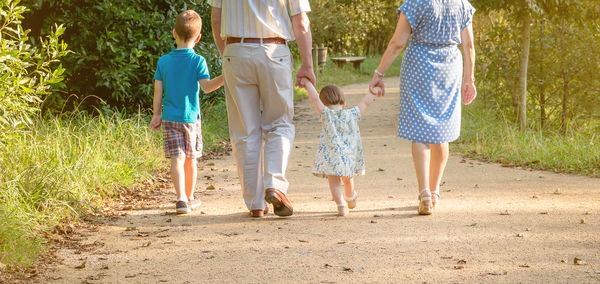 Low section of grandparents walking with grandchildren at park