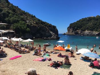 People at beach against clear blue sky