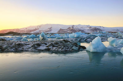 Scenic view of frozen lake against sky during sunset