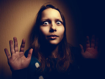 Portrait of shocked woman against wall at home