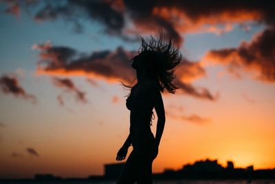 Silhouette woman against orange sky