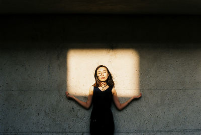 Portrait of woman standing against wall