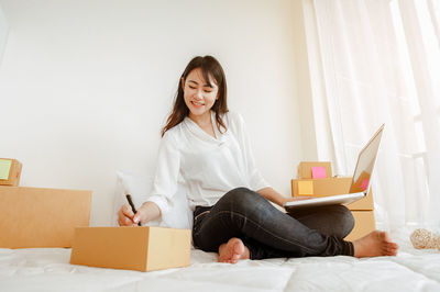 Young woman using phone while sitting in box