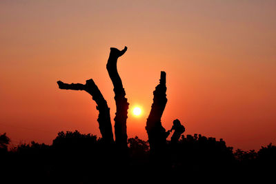 Silhouette people standing against orange sky