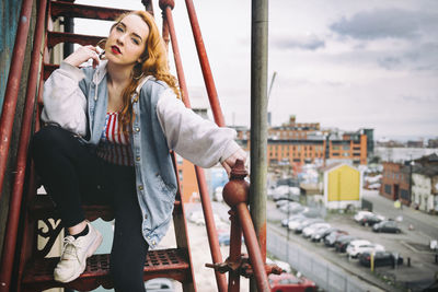 Young woman looking down while sitting on railing