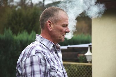 Close-up of man exhaling smoke outdoors