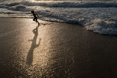 Silhouette boy running at beach