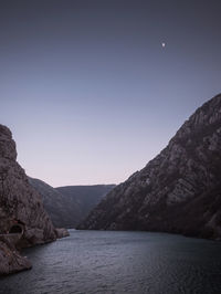 Scenic view of river amidst mountains against clear sky