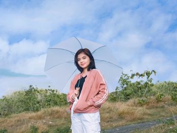 Portrait of smiling woman standing against sky