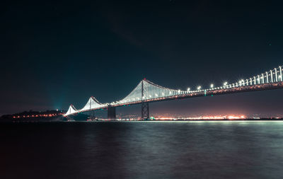 Illuminated suspension bridge over river at night