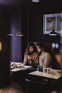 Woman using smart phone while male partner looking in hotel