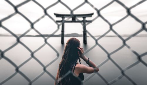Rear view of woman seen through chainlink fence