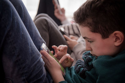 Boy using mobile phone while sitting with friends