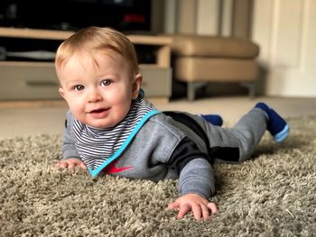 Portrait of cute boy lying on rug at home