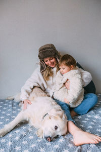 Mom and daughter comfortably cuddle at home with their pet labrador retriever