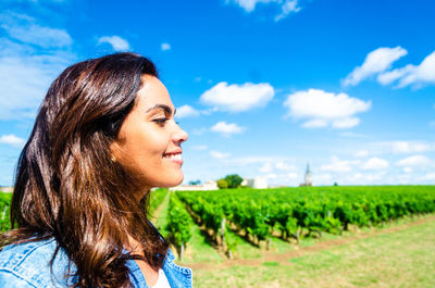 Portrait of smiling young woman on field against sky