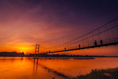 Bridge over river against sky during sunset