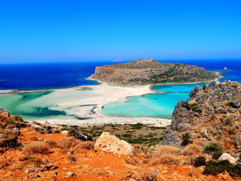 Scenic view of sea and mountains against clear blue sky