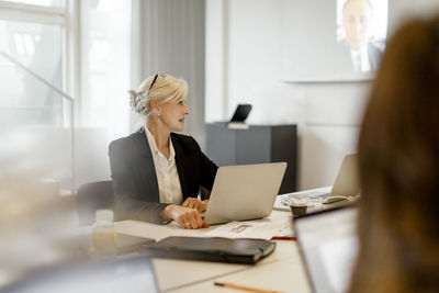 Mature businesswoman with laptop concentrating in conference meeting at board room