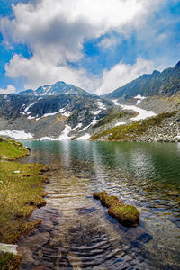 Scenic view of lake by mountains against sky