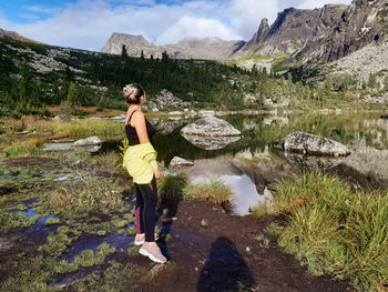 Rear view of woman standing on mountain against sky