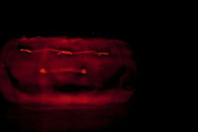 Close-up of illuminated red light against black background