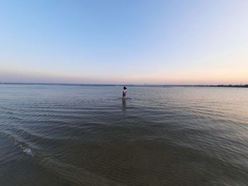 Woman standing on seashore against sky