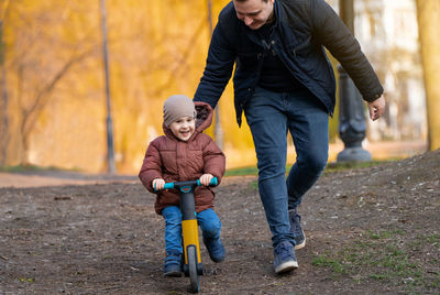 Happy father and son ride a bicycle in a park on a sunny day. having fun together with family 