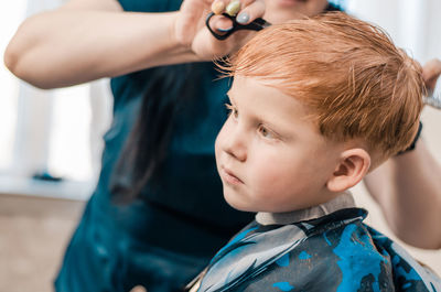 4 year old redhead boy at the barbershop. hairdresser cuts a child's hair