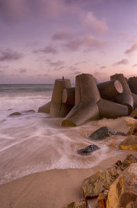 Rocks on beach against sky during sunset