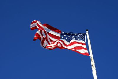 Low angle view of flag against blue sky