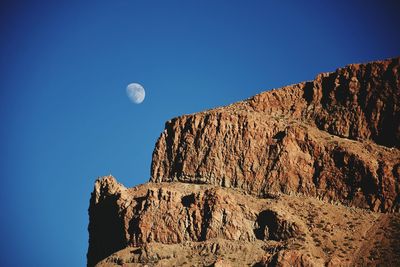 Low angle view of half moon against clear blue sky