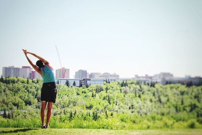 Rear view of woman standing on field against clear sky