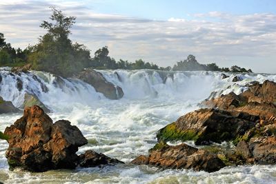 Scenic view of waterfall against sky